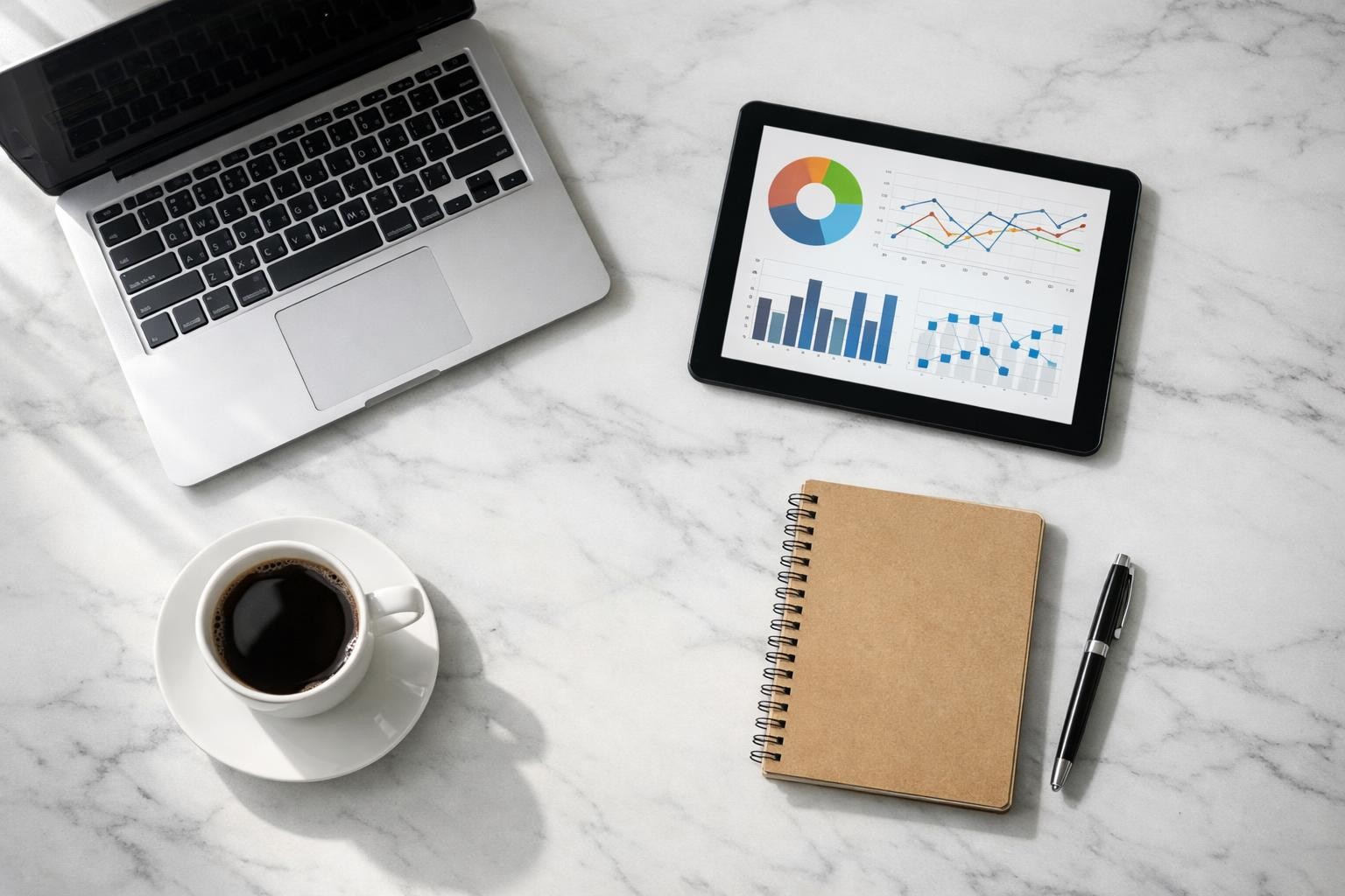 Overhead flat-lay of a modern workspace with laptop, tablet showing data charts, coffee cup, notebook and pen on a clean white marble desk, bright natural window light from the left creating soft shadows, shot on Fujifilm X-T5 with 23mm f/2 lens, absolutely no text, no letters, no words, no numbers, no writing, no watermark, no logo