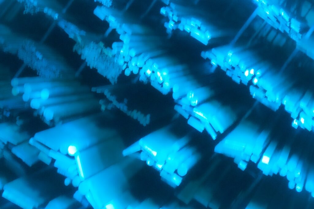 TSMC 2nm - A 3D isometric scene of a futuristic semiconductor fab with glowing nanosheet transistors, soft blue and pink p...