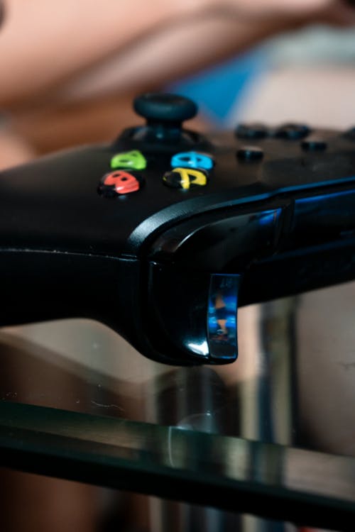 A 3D isometric scene of an adorable mascot holding a game controller in front of a desktop monitor showing a console-style full screen gaming UI, glowing green Xbox-like power button, mint and peach gradient lighting, Pixar style 8K, no text, no logos